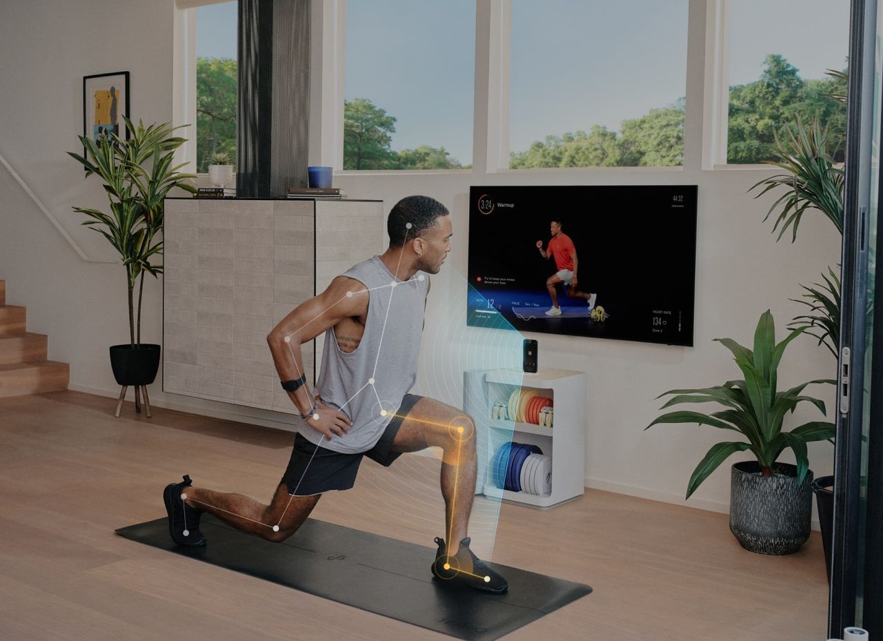 A man lunges on a mat in a bright living room, in front of a TV and a Tempo Move cabinet. Tracking lines follow his body, and the TV shows the class, a rep count and a form cue.