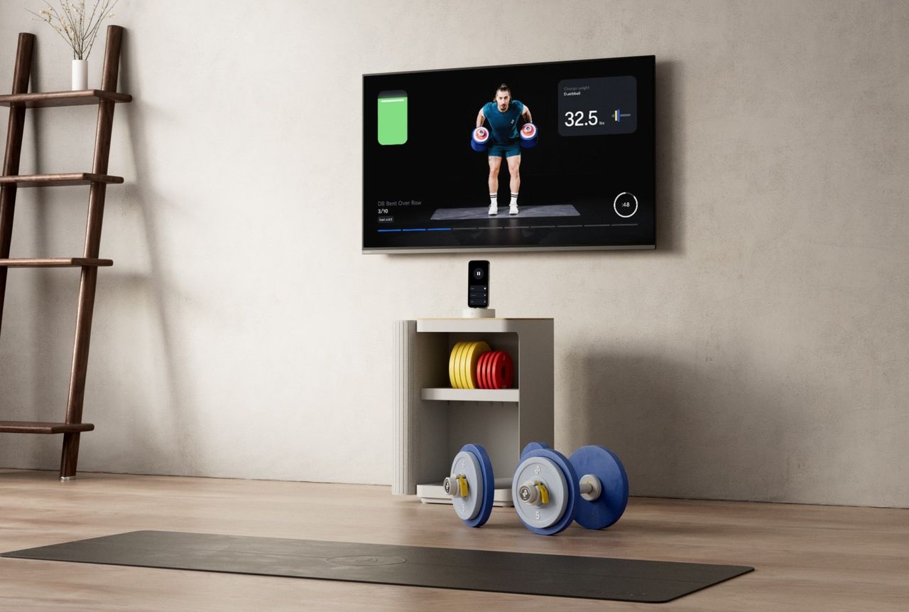 A Tempo Move cabinet holding plates and dumbbells under a wall-mounted TV showing a class.